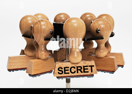 Molti francobolli appesa in un timbro rack. Un timbro con la scritta segreto si blocca nella parte anteriore, sfondo bianco. Foto Stock