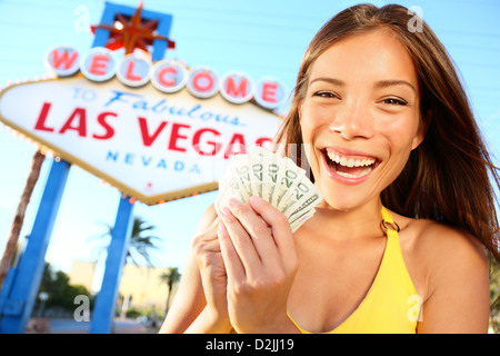 Giovane e bella gara di misto Caucasian / Chinese azienda asiatica denaro di fronte di Benvenuto nella favolosa Las Vegas segno Foto Stock