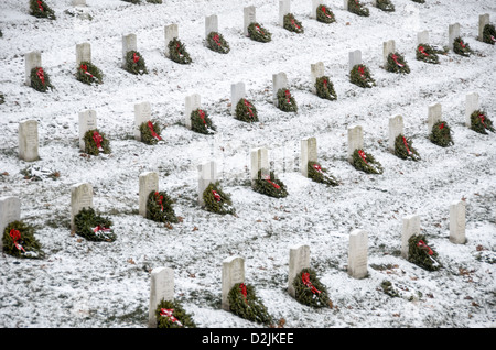 Lapidi presso il Cimitero Nazionale di Arlington nella neve. I volontari hanno aggiunto una ghirlanda di vacanza per ogni recinto. Arlington, Virginia, Stati Uniti. Foto Stock