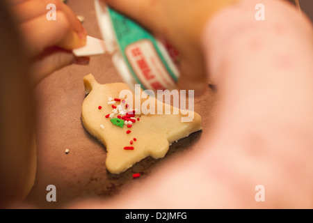 Una bambina decora biscotti di Natale prima della loro cottura Foto Stock