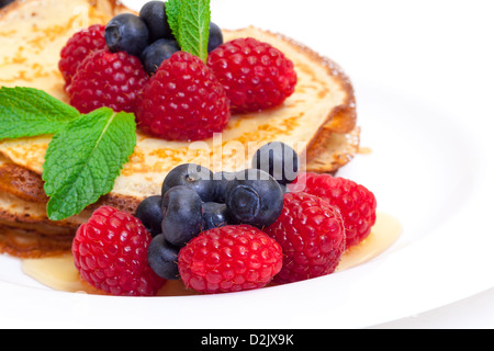 Delizioso preparato fresco frittelle con miele e frutti di bosco su sfondo bianco Foto Stock