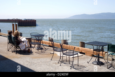 Giovane godendo la vista da tavoli e sedie sulla 39th Street Dock in Astoria, Oregon. Foto Stock