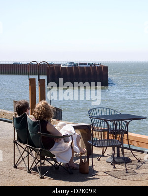 Giovane godendo la vista da tavoli e sedie sulla 39th Street Dock in Astoria, Oregon. Foto Stock