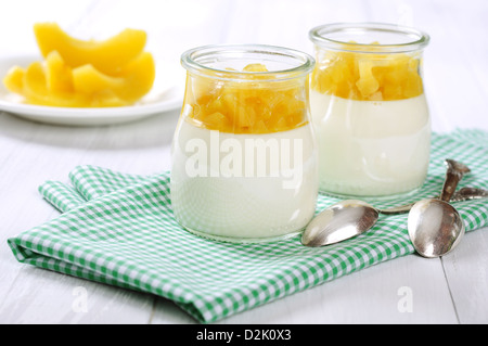 Dessert di frutta con mango in vasetti di vetro bianco su sfondo di legno Foto Stock