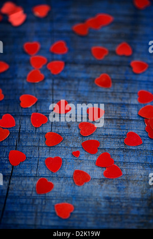 Rosso lucido di cuori blu su uno sfondo di legno Foto Stock