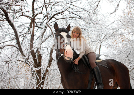 Ragazza bionda con il suo cavallo in un paesaggio di neve Foto Stock