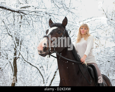 Ragazza bionda con il suo cavallo in un paesaggio di neve Foto Stock