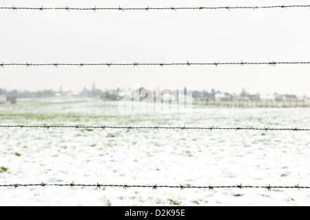 Filo spinato sul paese d'inverno sfondo Foto Stock