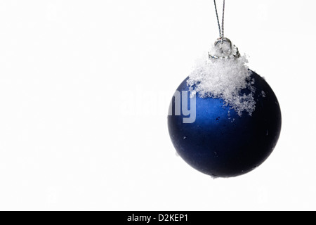A single silver and blue bauble against a snowy background. Foto Stock
