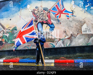 Il 27 gennaio 2013, Londonderry, Irlanda del Nord. Un giovane ragazzo protestante detiene una bandiera dell'Unione di fronte a una parete murale, copiati da Iron Maiden album 'il soldato'. Foto Stock