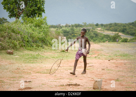 Benna boy correre e giocare in campo con cerchiatura di grandi dimensioni Foto Stock