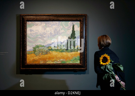 Donna che mantiene un girasole guarda al 1889 dipinto 'un Wheatfield, con cipressi di Vincent van Gogh Foto Stock