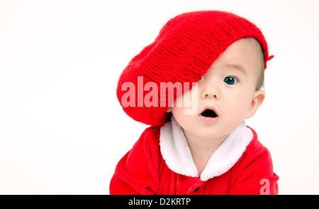 Carino Infant Boy in una composizione orizzontale strisciando nel vestito rosso e hat Foto Stock