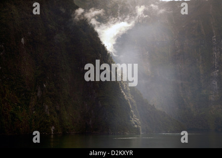 Luce di sole catture una nebbia di salita lungo le scogliere di suoni in Nuova Zelanda. Foto Stock
