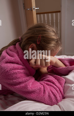 Giovane donna che indossa un rosa vestaglia, mano che copre il volto. Foto Stock