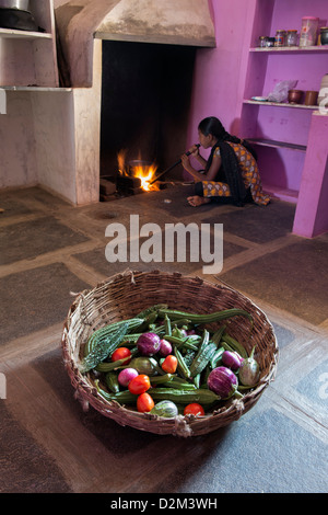 Cesto di verdure indiano e una ragazza di preparare il fuoco nella cucina di un territorio rurale villaggio indiano house. Andhra Pradesh, India Foto Stock