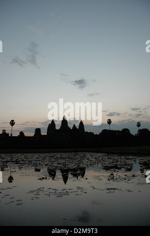 Sunrise oltre Angkor Wat in Cambogia mostra edificio in silhouette, riflesso nel laghetto di gigli Foto Stock