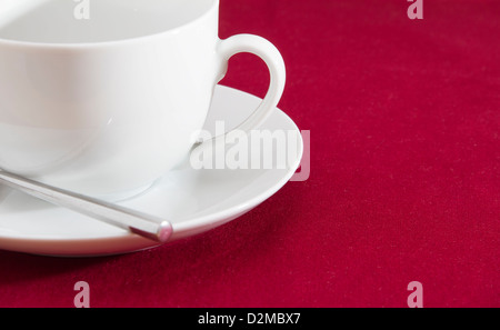 Tazza bianca con piattino sulla tovaglia rossa Foto Stock