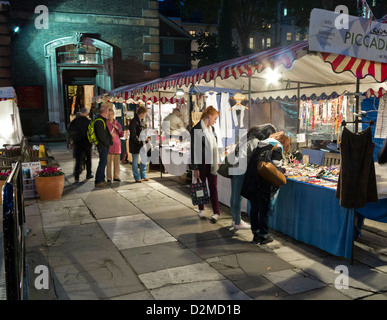 Esplorazione di persone a platea in Piccadilly Mercato dei motivi di St James's Chiesa, Londra di notte Foto Stock