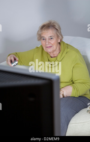 Coppia signora seduta tenendo premuto il telecomando, guardando la TV. Foto Stock