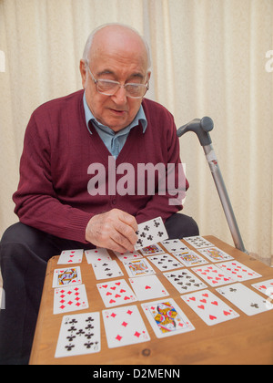 Pazienti anziani L'uomo maschio senior citizen carte da gioco sul suo proprio Foto Stock