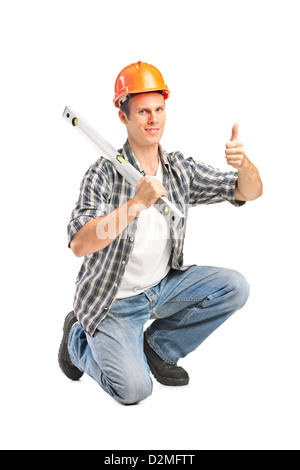 Un lavoratore sorridente tenendo una costruzione di livello a bolla e dando pollice in alto isolato su sfondo bianco Foto Stock