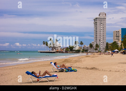 SAN JUAN, PUERTO RICO - Donne turisti guardando i telefoni intelligenti sulla spiaggia di Isla Verde. Foto Stock