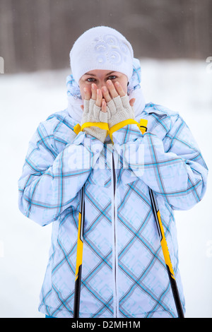 Giovane donna caucasica warming dita con bastoncini da sci in mani. Inverno Sciare Foto Stock