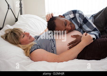 Bianco in gravidanza femmina e maschio nero ascolto al bimbo di heartbeat Foto Stock