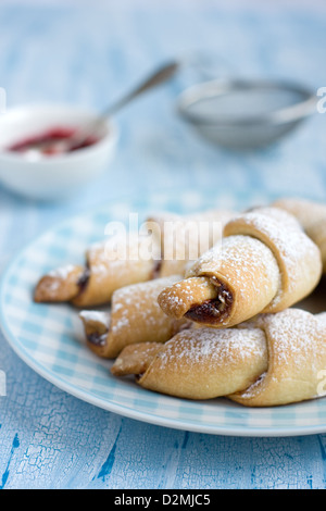 Rugelach con confettura di lamponi farcitura sulla luce piastra di blu Foto Stock