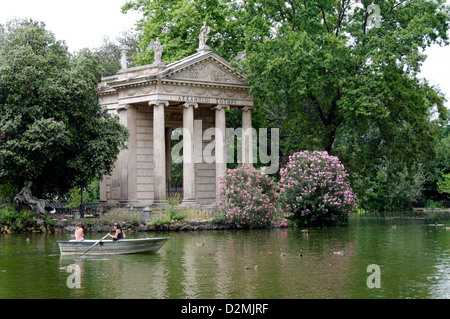 Roma. L'Italia. Persone in barche barca a remi intorno al tempio ionico di Esculapio. I giardini di Villa Borghese lago (Giardino dei Lago) Foto Stock