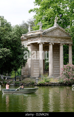 Roma. L'Italia. Persone in barche barca a remi intorno al tempio ionico di Esculapio. I giardini di Villa Borghese lago (Giardino dei Lago) Foto Stock