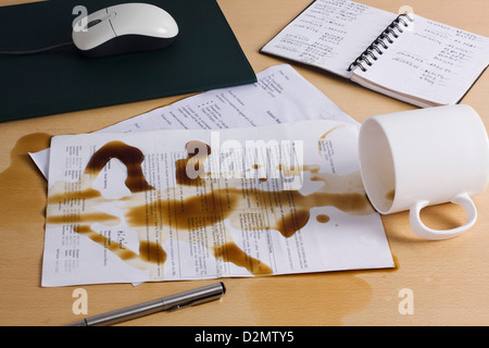 Ha versato del caffè su documenti su una scrivania Foto Stock