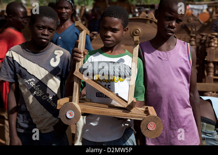 NAMPULA, Mozambico, Maggio 2010 : MERCATO DI DOMENICA - ragazzi la vendita di un bambino di legno a quattro ruote scooter. Foto di Mike Goldwater Foto Stock