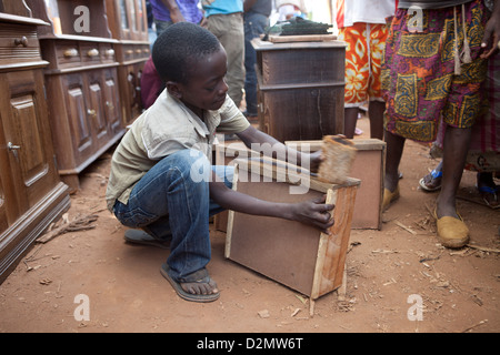 NAMPULA, Mozambico, Maggio 2010 : MERCATO DI DOMENICA - un ragazzo la lucidatura di un'estrazione frontale per un arredamento in legno venditore. Foto Stock