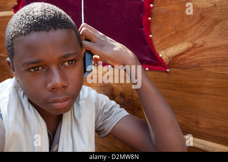 NAMPULA, Mozambico, Maggio 2010 : MERCATO DI DOMENICA - un ragazzo ascolta la sua radio mentre si lavora su una fase di stallo nel mercato dell'arredamento. Foto Stock