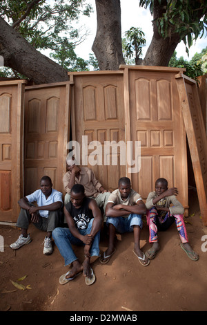 NAMPULA, Mozambico, Maggio 2010 : MERCATO DI DOMENICA - giovani uomini sedersi accanto le porte hanno messo in vendita nel mercato dell'arredamento. Foto Stock