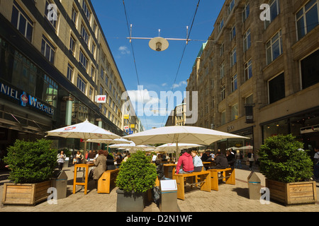 La gente seduta al fresco sotto gli ombrelloni fuori del ristorante sulla strada pedonale dello shopping, Spitalerstrasse, Amburgo, Germania Foto Stock