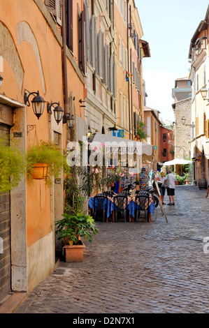 Roma. L'Italia. Vista di una stretta strada di ciottoli con una pizzeria in Trastevere. Foto Stock