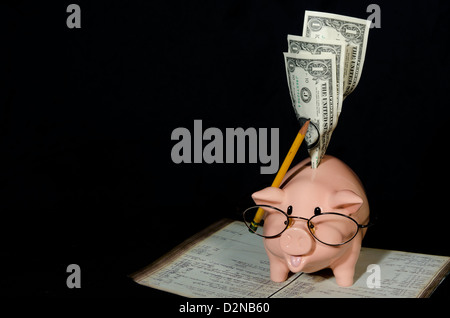 Questo piccolo salvadanaio è un contabile guardando attraverso il suo ledger di modi per risparmiare denaro e ridurre le spese. Foto Stock