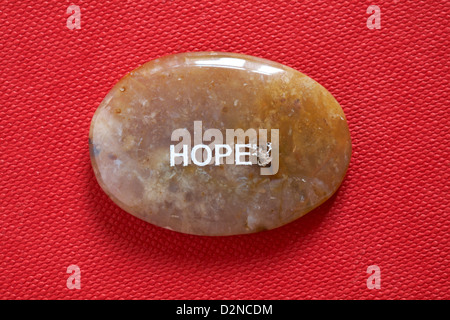 Il commercio equo e solidale sentimento ciottoli - speranza pebble isolato su sfondo rosso Foto Stock