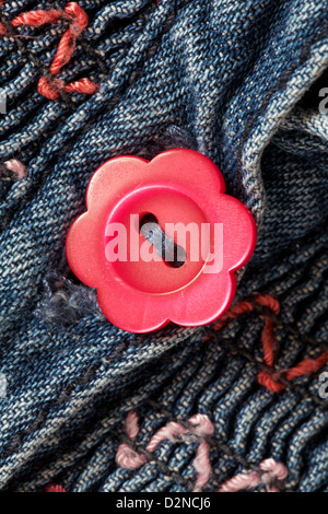 Daisy sagomato il pulsante rosso sulla piccola ragazza abito denim Foto Stock