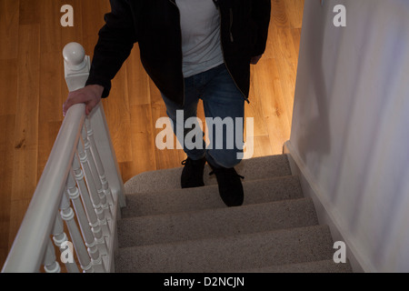 Giovane maschio che indossa jeans e una giacca nera e un teeshirt camminare da solo al piano di sopra la faccia (non mostrato). Foto Stock