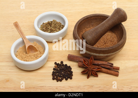 Ingredienti per il cinese cinque spezie con ramekins e un pestello e mortaio su una tavola di legno Foto Stock