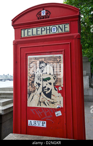 Una classica cabina telefonica rossa a Londra adornata da vibrante Street art, che mescola tradizione con la moderna cultura urbana Foto Stock