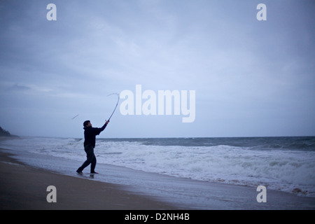 Pescatore sagomato che sorvola al crepuscolo sulle coste panoramiche di Montauk, un momento tranquillo che abbraccia il patrimonio ittico di Long Island Foto Stock