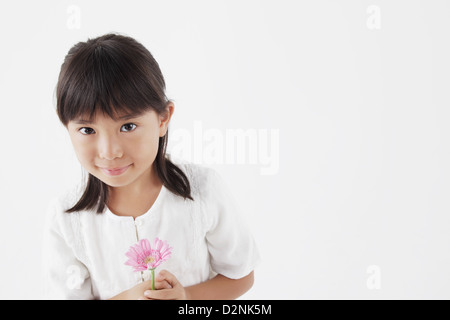 Ragazza in un abito bianco tenendo un fiore rosa Foto Stock