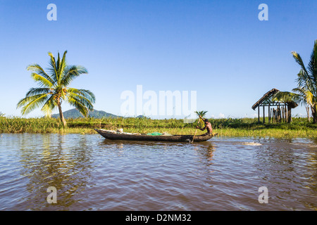 Uomo malgascio di etnia Betsimisaraka sguazzare nel suo in canoa lungo il fiume il Maggio 22, 2007 vicino a Maroantsetra in Madagasc orientale Foto Stock