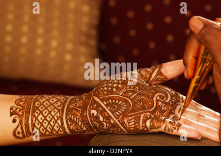 Donna di mano applicando henna sulla sposa il palmo della mano Foto Stock