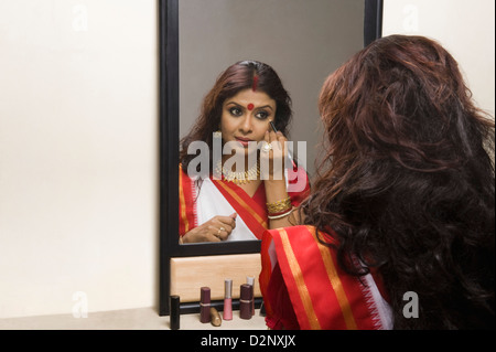 Donna di applicare eyeliner davanti a uno specchio Foto Stock